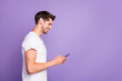© deagreez - Profile side view portrait of his he nice attractive cheerful cheery focused guy using cell chatting browsing web isolated over bright vivid shine vibrant violet lilac purple color background