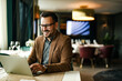 © bnenin - Happy man using laptop at restaurant, portrait.