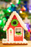 Fototapeta  - Gingerbread House On Table On Background Of Christmas Tree.
