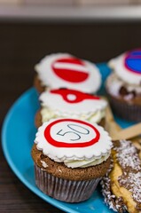 Sticker - Vertical shot of chocolate cupcakes with white frosting and traffic signs on a blue plate