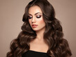 © Oleg Gekman - Brunette Girl with Long Healthy and Shiny Curly Hair. Care and Beauty. Beautiful Model Woman with Wavy Hairstyle. Make-Up and Black Dress