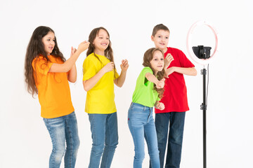 A group of children bloggers shoot video on the phone. Selfies The phone is mounted on a modern round lamp with a tripod.