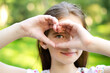 Smiling little girl holding hands near her eye with heart shape