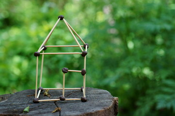 Toy house made of toothpicks on a wooden background.