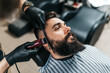 Young good looking man visiting barber shop. Trendy and stylish beard styling and cut.