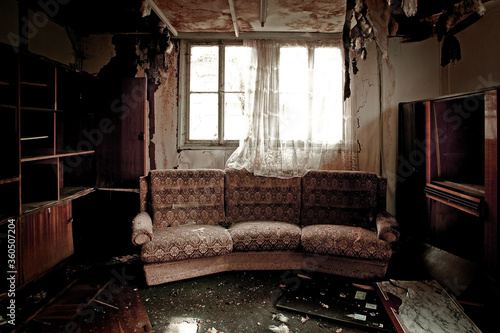 Room after a fire, view into a burnt out, dirty room with sofa
