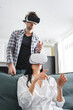 © LIGHTFIELD STUDIOS - Young couple pointing with fingers while using virtual reality headsets at home