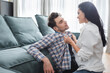© LIGHTFIELD STUDIOS - Selective focus of smiling woman holding shirt of handsome boyfriend near sofa in living room