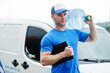 © AS Photo Family - Delivery man with clipboard in front cargo van delivering bottles of water.
