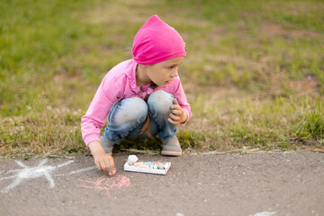 Wall Mural - The child drawing a chalk on asphalt. Child drawings paintings on asphalt concept.