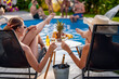 © ivanko80 - Two female friends drink champagne by swimming pool