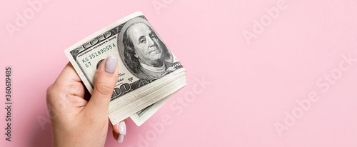 Fotografía A pack of one hundred dollar bills in female hand on colorful background