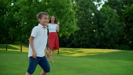 Wall Mural - Mother throwing ball in green field. Parents and kids playing with ball in park