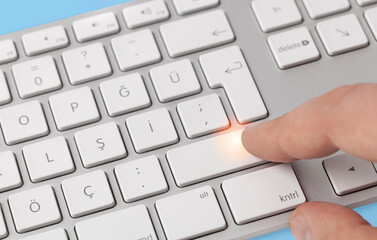 Male hand pressing computer keyboard enter key.Office worker concept.Blue table background