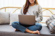 © Farknot Architect - Closeup image of a young woman using and working on laptop computer while sitting on a sofa at home