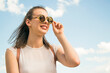 © Ahmed - Trendy girl in sunglasses posing over sky background, bright sunlight.