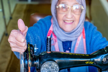 Arabic muslim old woman happy while using sewing machine