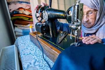 Wall Mural - Arabic muslim old woman using old sewing machine