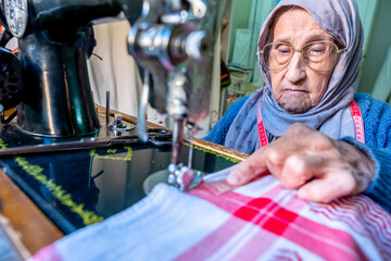 Wall Mural - Arabic muslim old woman using old sewing machine