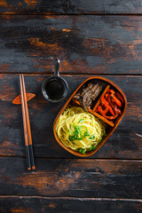 Wall Mural - Homemade Bento pack lunch, grilled beef and noodles with ingredients top view dark wooden table.
