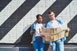 © BullRun - Caucasian young man together with african american hipster girl reading travel map to search right route during trip standing near wall with graffiti.Diverse couple in love tourists using smartphone