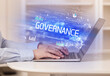 © ra2 studio - Closeup of businessman hands working on laptop with GOVERNANCE inscription, succesfull business concept
