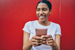 © BullRun - Cheerful dark skinned woman satisfied with good 4G connection chatting with friends online on smartphone, happy African American hipster girl holding mobile phone share multimedia in blog via app