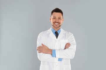 Happy man in lab coat on light grey background