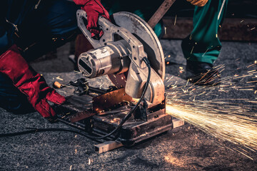 Wall Mural - Professional mechanic man is cutting steel metal with rotating carbon blade cutter. Steel industry and workshop concept.