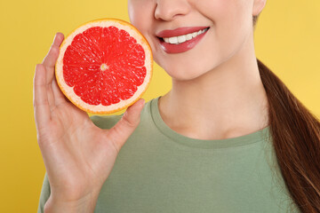 Sticker - Young woman with cut grapefruit on yellow background, closeup. Vitamin rich food