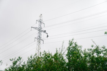 Male electricians make repairs on the electric tower. Power line against the sky.June 6, 2020 Saint-Petersburg, Russia