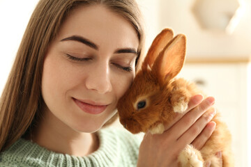 Wall Mural - Young woman with adorable rabbit indoors, closeup. Lovely pet