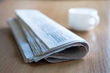 Fototapeta  - Folded newspaper on a wooden table with coffee