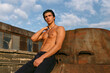 © Dragosh - Closeup of a sexy male model with tanned skin posing with naked torso outside, showing six pack abs at the sunset light and clouds background.