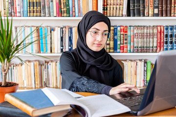 Wall Mural - Arabic muslim woman using laptop for online meetings and studying