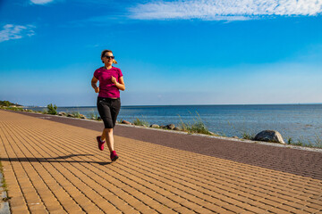 Wall Mural - middle-aged woman running by sea shore