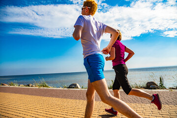 Wall Mural - Woman and man running by sea shore