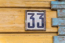 The Sign Number 33 On The Corner Of An Old Wooden House Painted Yellow And Blue The Paint Has Come Off