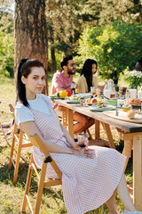 Wall Mural - Pretty young brunette woman in casualwear sitting on chair by served table