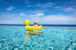 Ein kleines Baby mit Sonnenhut sitzt in seiner Schwimmente und treibt auf dem Swimming Pool an einem heißen Sommertag