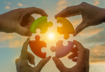 Four hands of businessmen connect colored pieces of the puzzle into a single whole. Business concept idea, partnership, cooperation, teamwork, creative, innovation