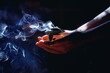 © jozefklopacka - incense in a woman hand, incense smoke on a black background.