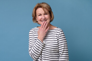 Mature caucasian woman laughing covering mouth with hand. Successful middle aged woman looking at camera.