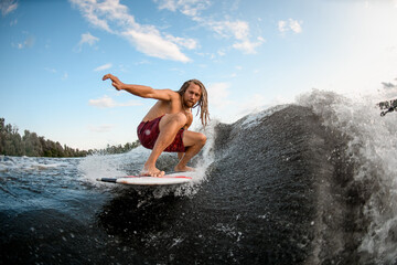 Wall Mural - Athletic young man wakesurfing down the river waves