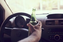 Man Driving A Car While Holding A Bottle Of Beer. Drunk Diving, Unsafe Driving Concept