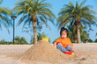 © sorapop - Asian Thai happy cute little cheerful daughter girl funny digging playing toy with sand at an outdoor tropical beach in summer day with copy space