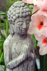 Canvas Print - Closeup shot of the statue of Buddha with pink flowers