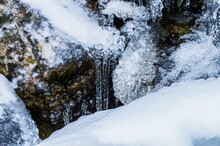 Closeup Shot Of Flowing Water With A Frozen Rock During Winter