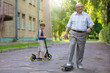 © Светлана Лазаренко - Grandfather and grandson on a walk. A child is watching his grandfather ride on a skateboard.