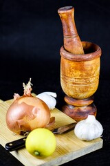 Canvas Print - Vertical shot of a wooden mortar and pestle and garlic, onion and lemon on wooden chopping board